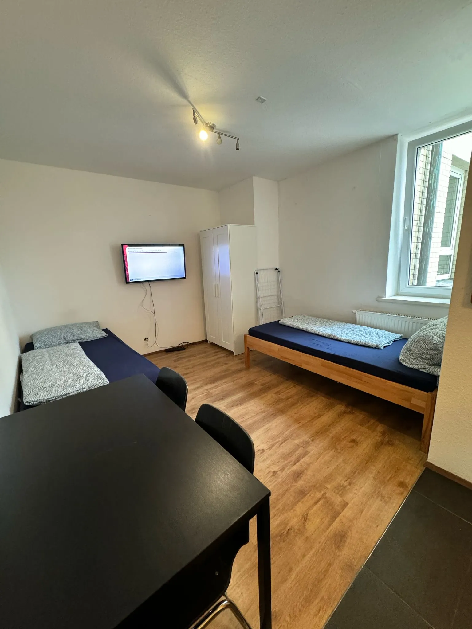 Geräumiges Doppelzimmer einer Monteurwohnung in Geislingen mit zwei Einzelbetten, Kleiderschrank und Wand-TV.