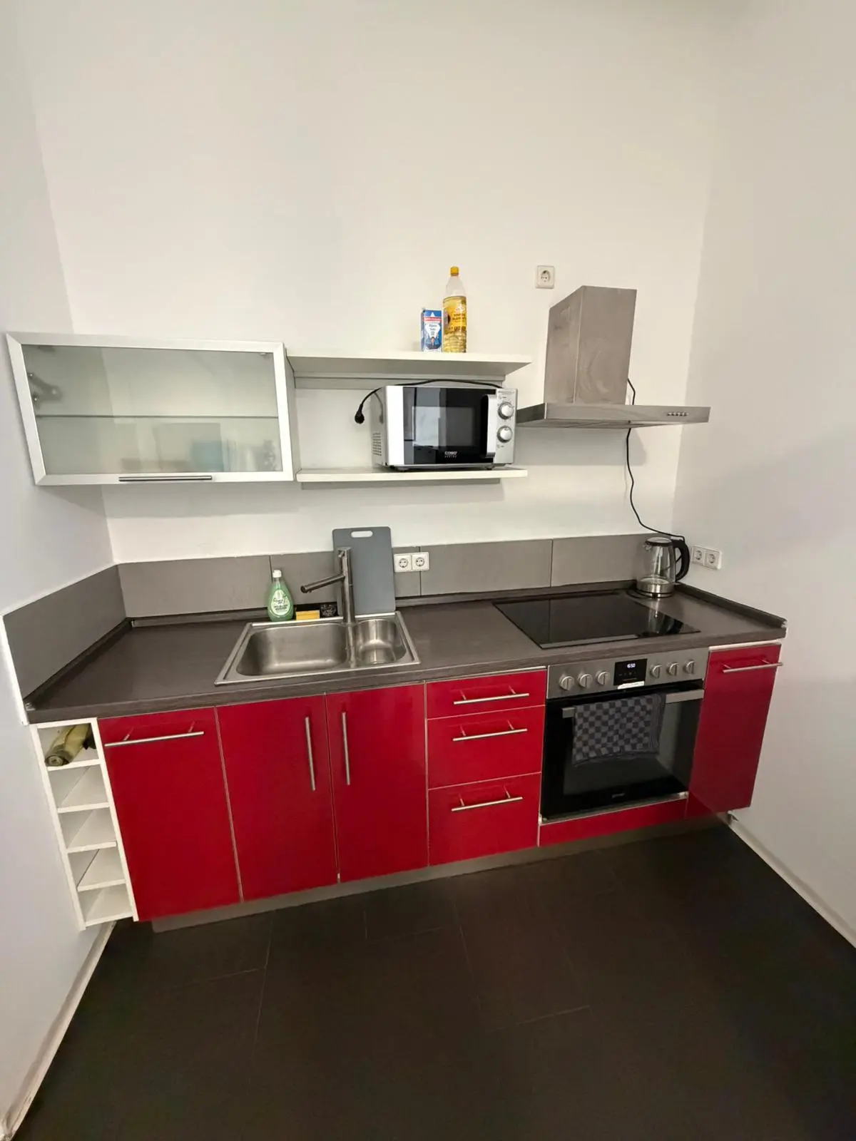 Voll ausgestattete rote Einbauküche mit Herd, Backofen und Mikrowelle in einer Monteurwohnung in Geislingen.