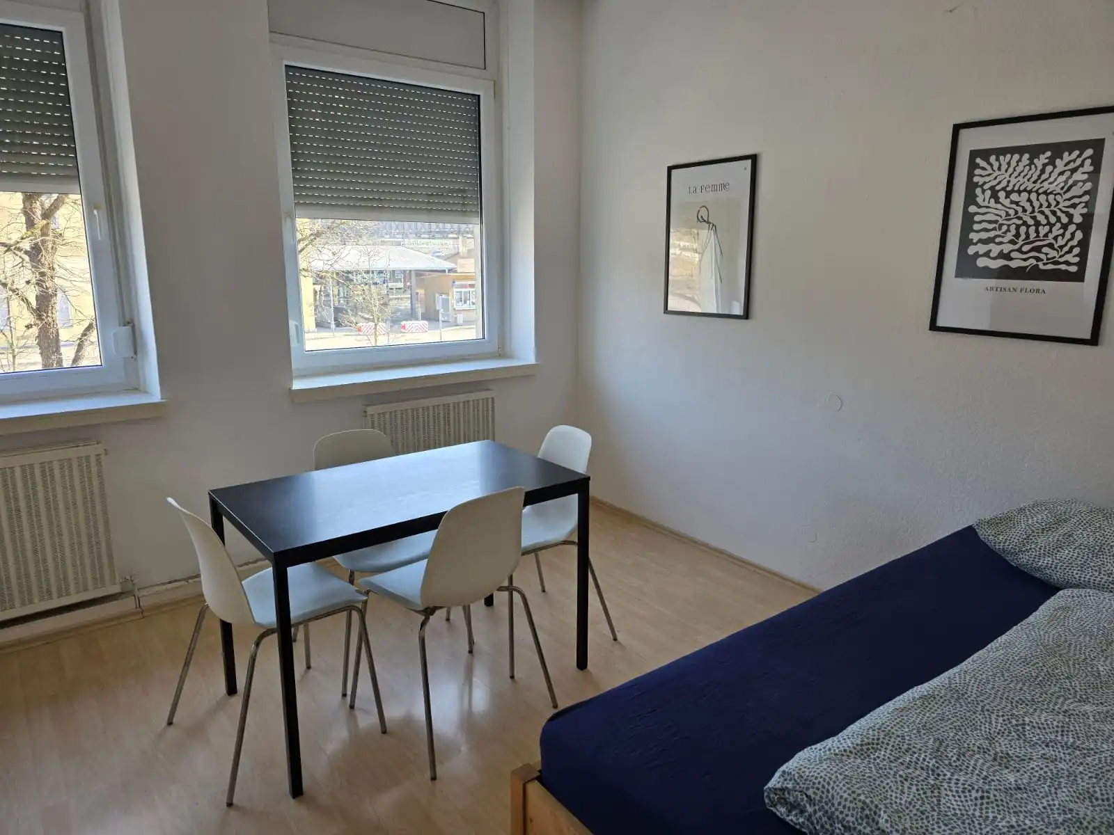 Gemütlicher Essbereich mit schwarzem Tisch und vier Stühlen direkt am Fenster in einer Geislinger Monteurwohnung.