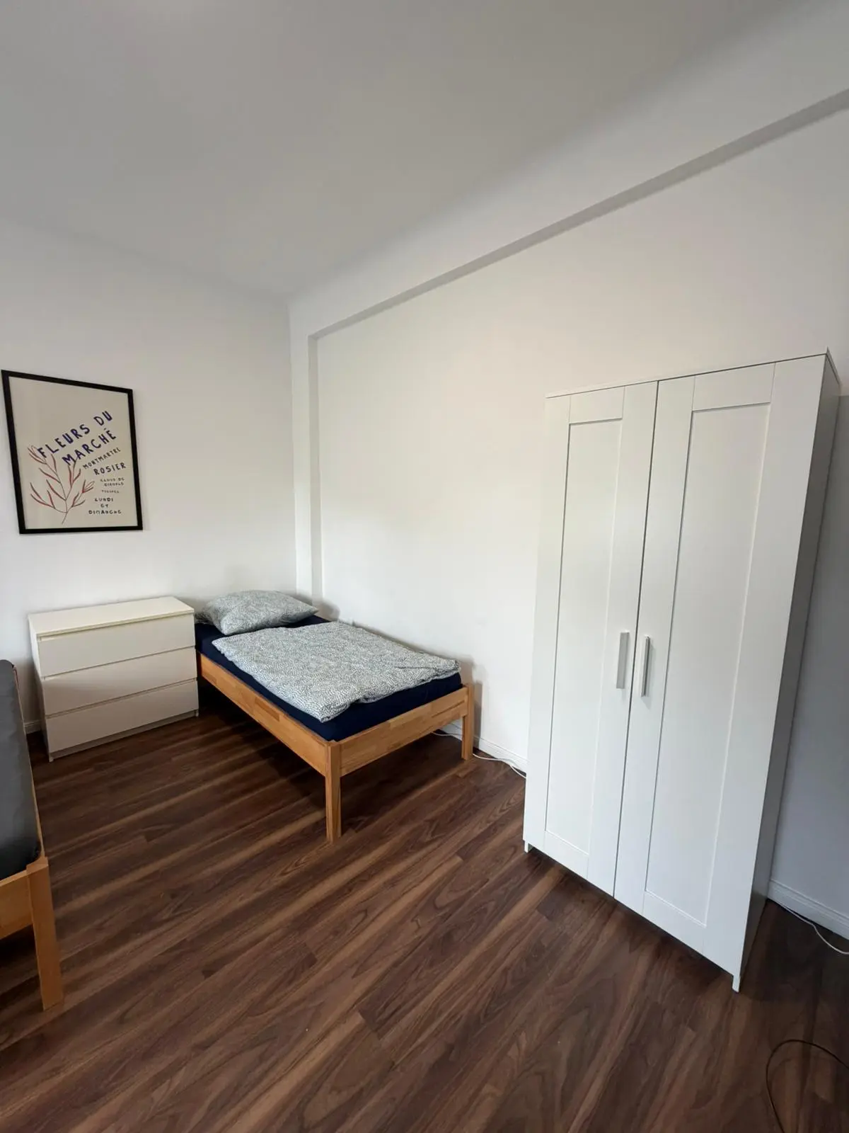Schlafbereich für Handwerker in Geislingen mit Einzelbett, weißem Kleiderschrank und Kommode.