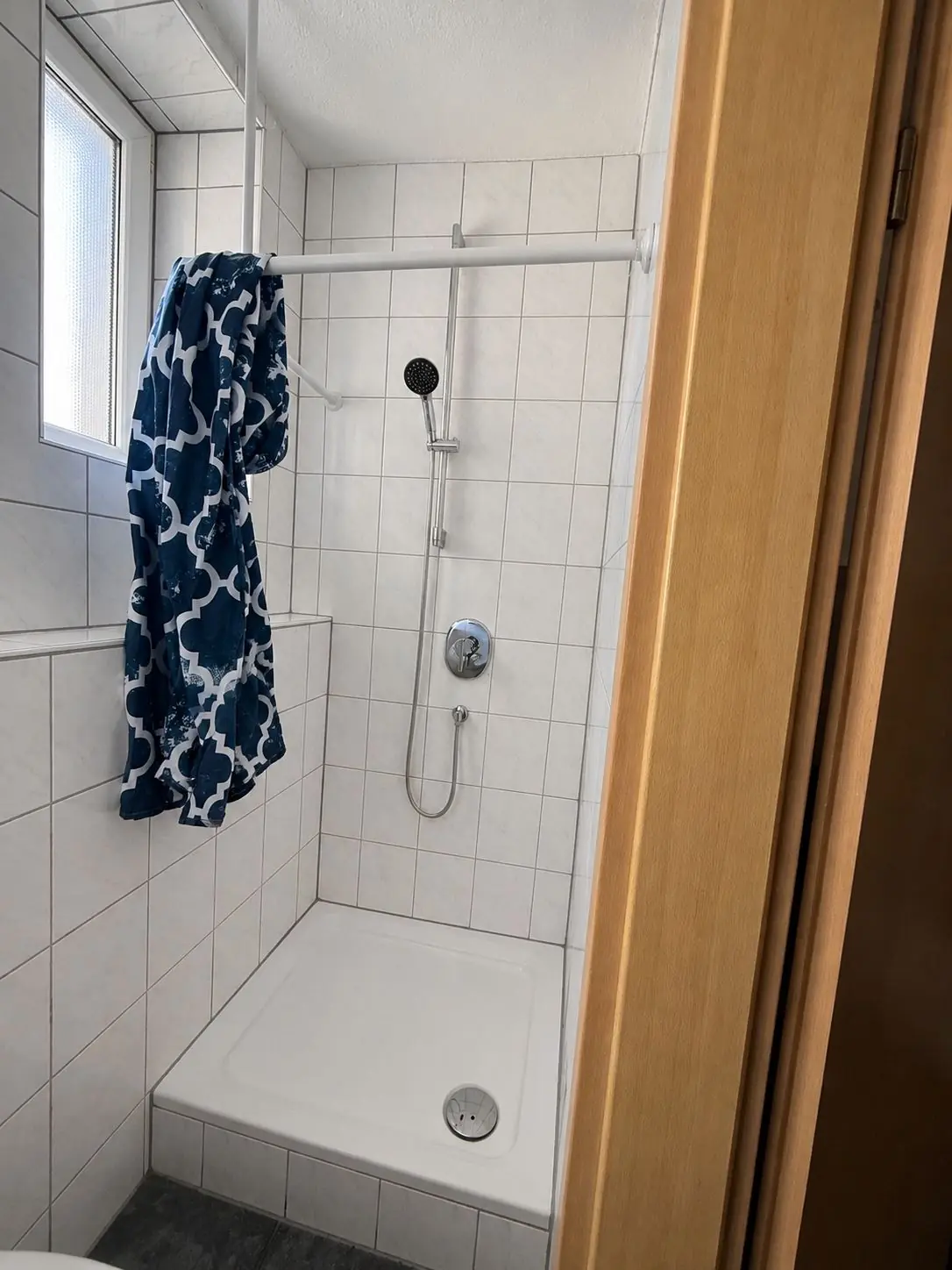 Saubere, helle Dusche mit Duschvorhang in einem gefliesten Badezimmer unserer Monteurunterkunft.