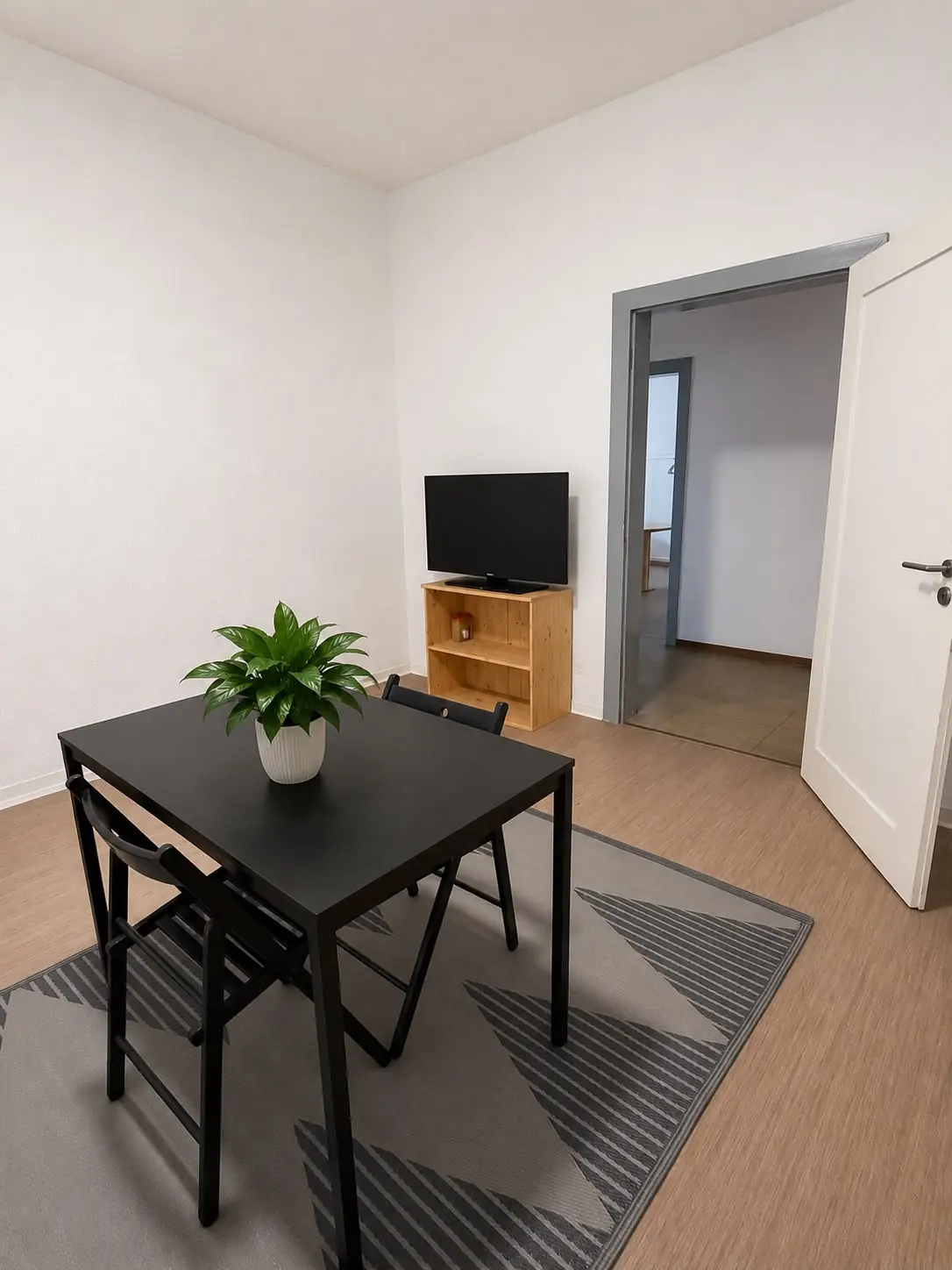 GEsszimmer mit Tisch, Fernseher und möbliertem Wohnbereich in moderner Unterkunft auf Zeit