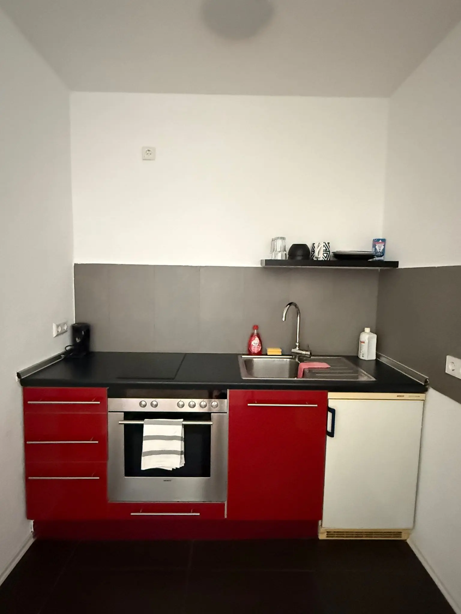 Funktionale Einbauküche mit Herd, Backofen, Kühlschrank und Spüle in einem Monteurzimmer zur Selbstversorgung.